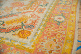 Vintage Oushak rug border with scrolling palmettes in saffron yellow, blush, and dusty teal.
