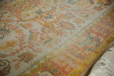 Blush, saffron, and dusty teal palmette border on vintage Oushak carpet.
