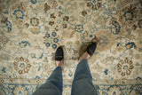 Overhead view of the distressed, low-pile texture of a vintage Tabriz carpet underfoot.