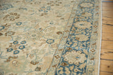 Angled view showing the distressed low pile and floral border of a vintage Tabriz carpet.