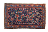 Vintage Persian Malayer rug with an allover gem-tone floral and bird design on a navy blue field.