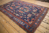 Angled perspective of a vintage Persian Malayer rug with gem-tone floral and bird motifs.