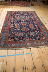 Low angle perspective of a vintage Malayer rug, highlighting its gem-toned floral patterns and navy field.