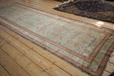 Distressed Malayer runner corner: pale teal Herati pattern, faded raspberry-red borders, visible wear.