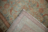 Distressed Malayer rug corner with dusty teal Herati design, pile wear revealing foundation, and hand-knotted back.