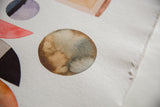 Textured handmade paper showing a brown-grey watercolor circle and deckled edge.