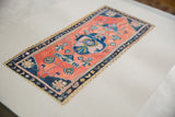 Detail of hand-painted rug artwork, blue border, peach field, and textured deckled paper.