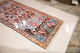 Angled view of Sarah Martinez rug print, colorful geometric and curvilinear motifs, faux fringe.