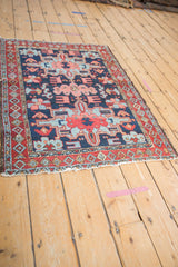 Angled view of a Karaja rug corner, detailing the red pearl border and visibly worn edge.