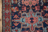 Detail of the geometric diamond border and stylized blossoms of a vintage Persian Karaja rug.