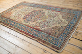 Angled view of a distressed Malayer rug with its scalloped medallion and sky blue border.