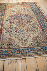 Angled perspective on a vintage Malayer rug, showing the even wear and paisley boteh motifs.