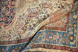 Softly draping vintage Malayer rug showing worn texture, paisley motifs, and a rich blue border.