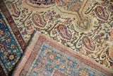 Corner of a distressed Malayer rug folded to show the hand-knotted back and the paisley boteh pile.