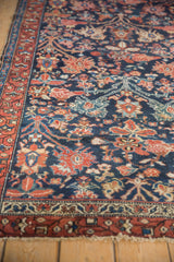 Vintage Hamadan rug detail: navy field with blossom vinery, rust border, and tattered edge.