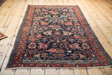Vintage Hamadan rug with madder red border, intricate vinery, and worn side edge.
