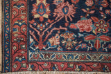 Hamadan rug corner: navy field with vinery, floral palmettes, madder root red border, frayed edge.