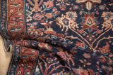 Folded vintage Hamadan rug displaying navy field, delicate blush palmettes, and rust geometric border.