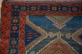 Kurdish Hamadan rug corner, madder red border, geometric arrowed finials on indigo blue field.