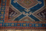 Kurdish Hamadan rug corner: abrashed indigo field, madder root red geometric border, splayed medallion.
