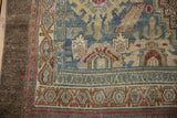 Distressed Bibikabad carpet corner: worn brown selvage, geometric borders, dusty teal, sand tones.