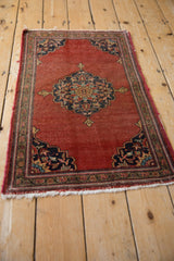 Persian Farahan Sarouk rug with brick red field, scalloped navy spandrels, and aged fringe.