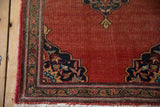 Vintage Farahan Sarouk rug corner: navy blue scalloped spandrel, floral motifs, tattered fringe.