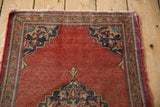 Vintage Farahan Sarouk rug's brick red field, scalloped corner, and patterned border with visible wear.