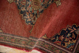 Rolled edge of vintage Farahan Sarouk rug displaying worn brick red field, traditional navy, gold border, and scalloped corner.