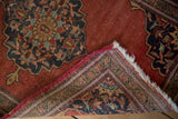 Vintage Farahan Sarouk rug corner showing brick red pile, worn magenta side, and woven back.