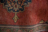 Vintage Farahan Sarouk rug, brick red field, dark navy curvilinear spandrel, and visible pile wear.