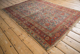Antique Malayer rug corner showing worn Herati pattern, cherry red border, tattered fringe.