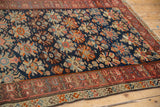 Vintage Caucasian rug close-up: geometric border, navy blue field with floral palmettes.
