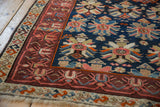 Vintage Caucasian rug corner, geometric borders, navy field with stylized palmettes, even pile wear.