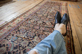 Angled view of a vintage Mahal runner highlighting its worn texture and complex Herati design.