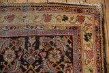 Corner view of a vintage Mahal runner showing the vine and blossom border and worn, low-pile texture.