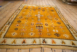 Vintage Moroccan rug's ivory border and saffron field, showcasing geometric blossoms and guls.