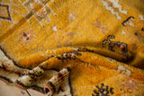 Saffron yellow, ivory, and brown geometric guls on a vintage Moroccan rug's shaggy pile.
