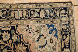 Vintage distressed Malayer rug corner: navy blue border, pale field with floral palmette motifs.