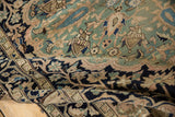 Folded vintage distressed Malayer rug showcasing even wear with jade green floral motifs.