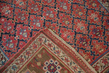 Kurdish runner's folded corner revealing cherry red geometric trellis and unique brown palmette border.
