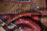 Folded antique Azeri rug showing madder red, sapphire blue, camel tribal geometric patterns.