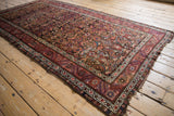 Corner of antique Northwest Persian rug with wine red geometric border and fringed end.