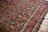 Antique Northwest Persian rug corner with complex Herati pattern, ruby red border, and fringe.