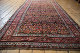 Angled view: Antique Northwest Persian rug featuring Herati design with rich chocolate and wine tones.