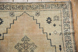 Distressed Senneh rug with stepped ivory field, charcoal geometric borders, and dusty rose undertones.