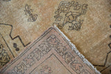 Distressed Senneh Baft rug corner showing low ivory pile and intricate woven rose-toned foundation.