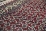 Low angle on the chestnut red field with boteh motifs and detailed ivory border.