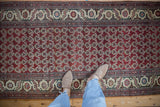 Overhead view of a vintage Hamadan runner with a chestnut red boteh pattern and decorative ivory border.
