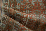 The soft, low pile and even wear of a folded vintage Karaja runner in rust, dusty blue, and ivory tones.
